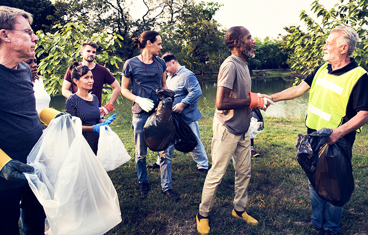 A group of volunteers cleaning up trash by a lake.